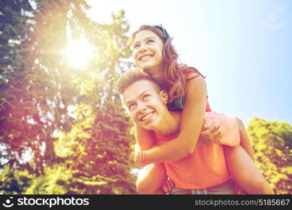 holidays, vacation, love and people concept - happy smiling teenage couple having fun at summer park. happy teenage couple having fun at summer park