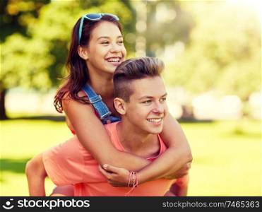 holidays, vacation, love and people concept - happy smiling teenage couple having fun at summer park. happy teenage couple having fun at summer park