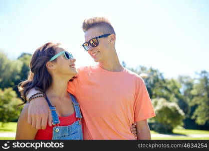 holidays, vacation, love and people concept - happy smiling teenage couple hugging and looking at each other at summer park