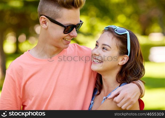 holidays, vacation, love and people concept - happy smiling teenage couple hugging and looking at each other at summer park