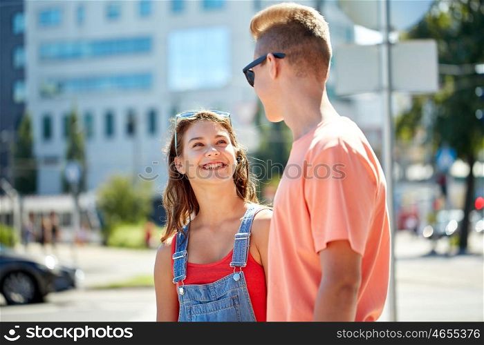 holidays, vacation, love and people concept - happy smiling teenage couple hugging and looking at each other at summer city. happy teenage couple looking at each other in city