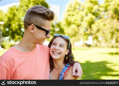 holidays, vacation, love and people concept - happy smiling teenage couple hugging and looking at each other at summer park