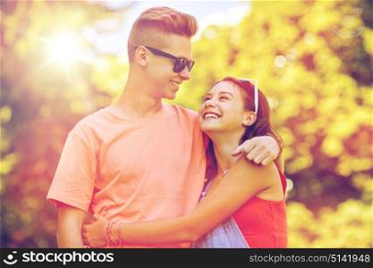 holidays, vacation, love and people concept - happy smiling teenage couple hugging and looking at each other at summer park. happy teenage couple looking at each other in park
