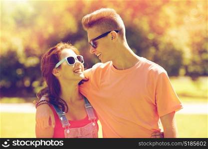 holidays, vacation, love and people concept - happy smiling teenage couple hugging and looking at each other at summer park. happy teenage couple looking at each other in park