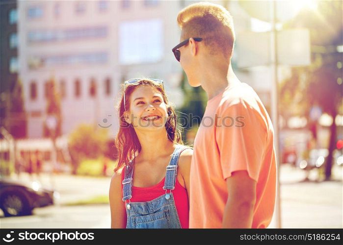 holidays, vacation, love and people concept - happy smiling teenage couple hugging and looking at each other at summer city. happy teenage couple looking at each other in city