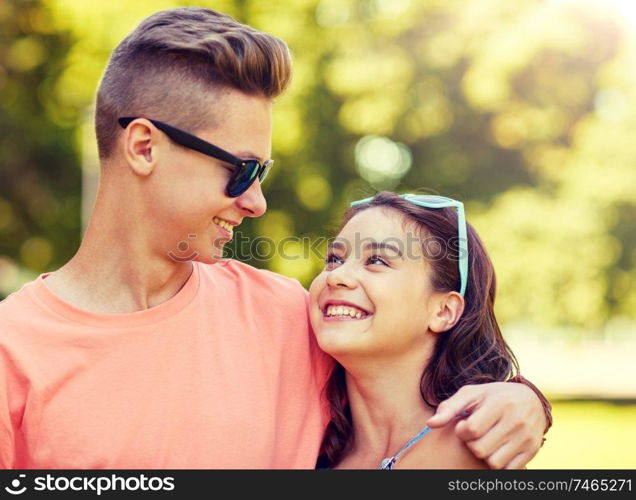 holidays, vacation, love and people concept - happy smiling teenage couple hugging and looking at each other at summer park. happy teenage couple looking at each other in park