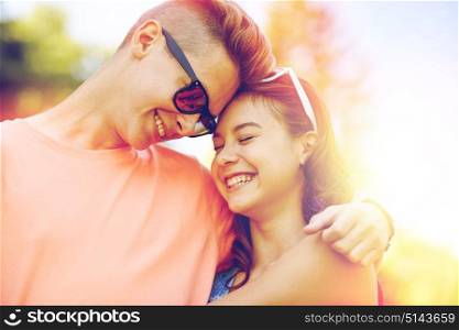 holidays, vacation, love and people concept - happy smiling teenage couple hugging at summer. happy teenage couple hugging at summer