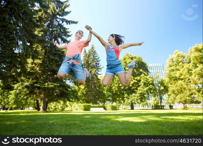 holidays, vacation, love and people concept - happy smiling teenage couple jumping at summer park