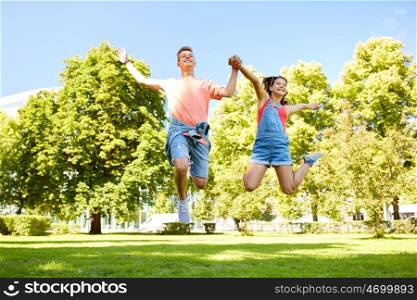 holidays, vacation, love and people concept - happy smiling teenage couple jumping at summer park