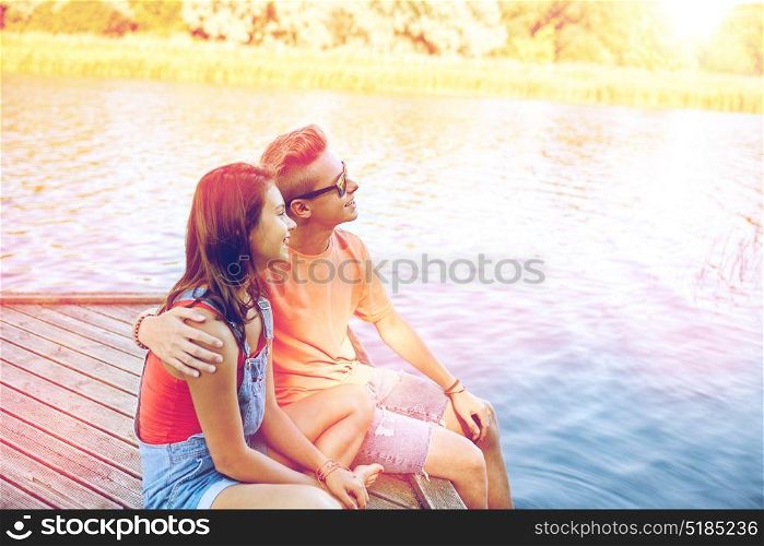 holidays, vacation, love and people concept - happy teenage couple hugging on river berth at summer. happy teenage couple hugging on river berth
