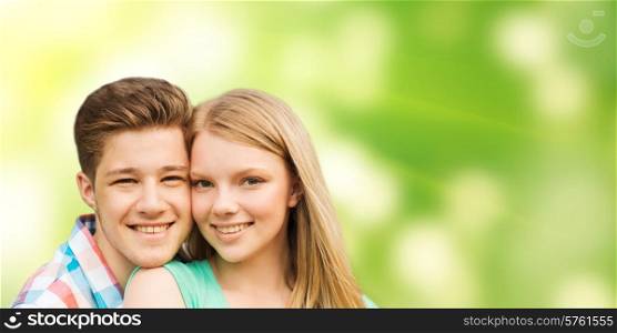 holidays, vacation, love, ecology and people concept - smiling teenage couple hugging over green background