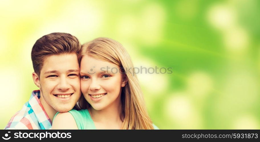 holidays, vacation, love, ecology and people concept - smiling teenage couple hugging over green background