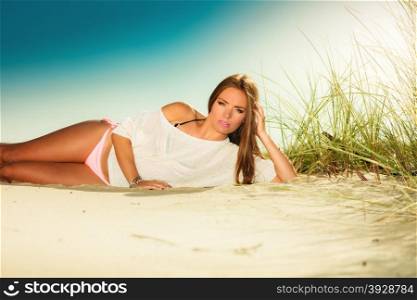 Holidays, vacation tourism and beauty concept. Attractive girl long haired on sandy beach. Tanned woman in summer clothing relaxing on the sea shore, blue sky