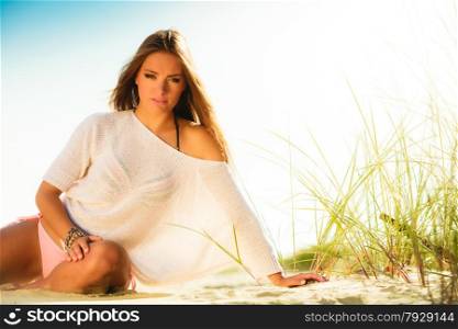 Holidays, vacation tourism and beauty concept. Attractive girl long haired on sandy beach. Tanned woman in summer clothing relaxing on the sea shore