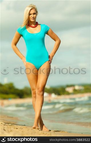 Holidays, vacation travel and freedom concept. attractive blonde girl in full length wearing blue swimsuit red beads relaxing on beach walking, having fun on hot summer day
