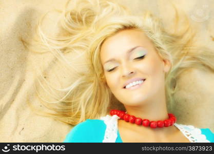 Holidays, vacation travel and freedom concept. Beautiful blonde girl laying on sandy beach, portrait