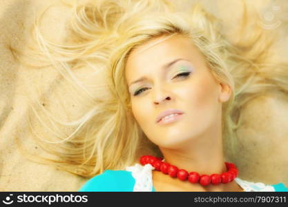 Holidays, vacation travel and freedom concept. Beautiful blonde girl laying on sandy beach, portrait