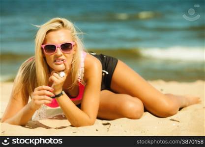 Holidays, vacation travel and freedom concept. Beautiful blonde tanned sexy girl on beach. Young woman in pink sunglasses relaxing on the sea coast.