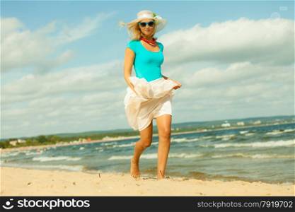 Holidays, vacation travel and freedom concept. Beautiful girl in summer clothing hat running on beach. Young woman having fun relaxing on the sea coast.