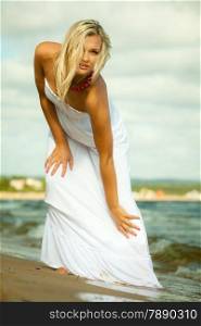 Holidays, vacation travel and freedom concept. Beautiful girl in white dress posing on beach. Young woman relaxing on the sea coast.