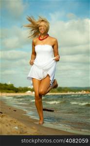 Holidays, vacation travel and freedom concept. Beautiful girl in white dress running on beach. Young woman having fun relaxing on the sea coast.