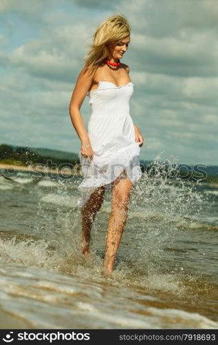 Holidays, vacation travel and freedom concept. Beautiful girl in white dress running on beach. Young woman having fun relaxing on the sea coast.