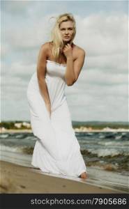 Holidays, vacation travel and freedom concept. Beautiful girl in white dress walking on beach. Young woman relaxing on the sea coast.
