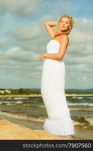 Holidays, vacation travel and freedom concept. Beautiful girl in white dress walking on beach. Young woman relaxing on the sea coast.