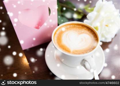 holidays, valentines day and love concept - close up of greeting card with heart, flower and coffee over snow