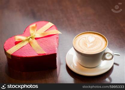 holidays, valentines day, love and drinks concept - close up of gift box and coffee cup on table
