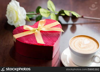 holidays, valentines day, love and drinks concept - close up of gift box, coffee cup and flower on table