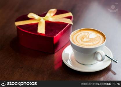 holidays, valentines day, love and drinks concept - close up of gift box and coffee cup on table