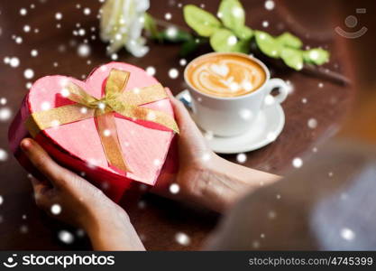 holidays, valentines day, love and people concept - hands holding heart shaped gift box over snow
