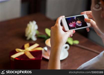 holidays, valentines day, technology and people concept - close up of hands with smartphone taking heart shaped gift box and coffee cup picture