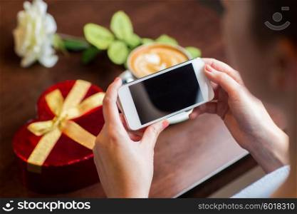 holidays, valentines day, technology and people concept - close up of hands with smartphone, gift box and coffee cup
