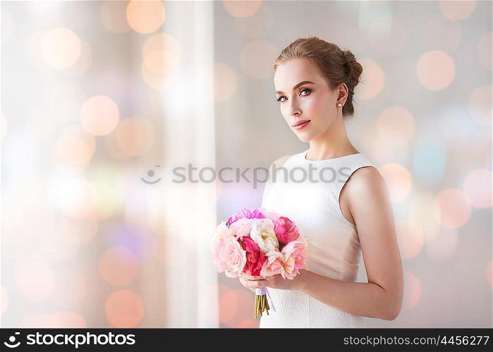 holidays, wedding and people concept - bride or woman in white dress with flower bunch over lights effect