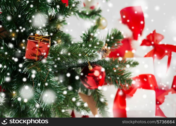 holidays, winter and celebration concept - close up of christmas tree and presents over gray background with snow