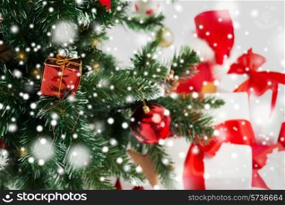 holidays, winter and celebration concept - close up of christmas tree and presents over gray background with snow