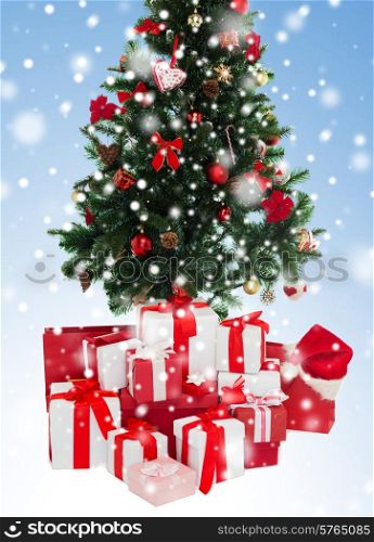 holidays, winter and celebration concept - f christmas tree and presents over blue background with snow