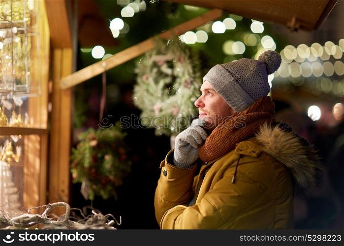 holidays, winter and people concept - happy man looking at christmas market shop window and choosing souvenir. happy man looking at christmas market shop window