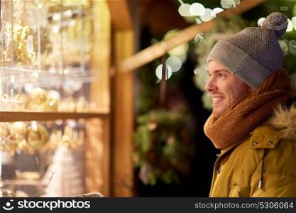 holidays, winter and people concept - happy man looking at christmas market shop window. happy man looking at christmas market shop window