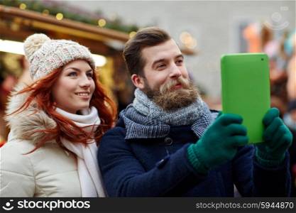 holidays, winter, christmas, technology and people concept - happy couple of tourists in warm clothes taking selfie with tablet pc computer walking in old town