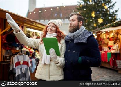 holidays, winter, christmas, technology and people concept - happy couple of tourists in warm clothes with tablet pc computer pointing finger in old town