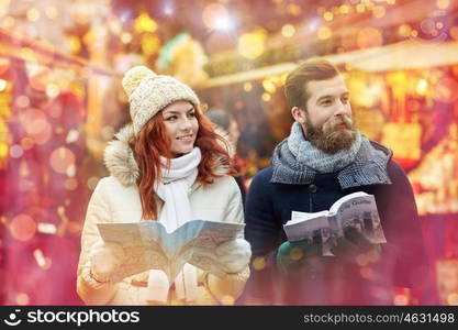 holidays, winter, christmas, tourism and people concept - happy couple in warm clothes with map and city guide in old town