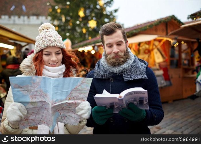 holidays, winter, christmas, tourism and people concept - happy couple in warm clothes with map and city guide in old town