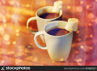 holidays, winter, food and drinks concept - close up of cups with hot chocolate or cocoa drinks and marshmallow on wooden table