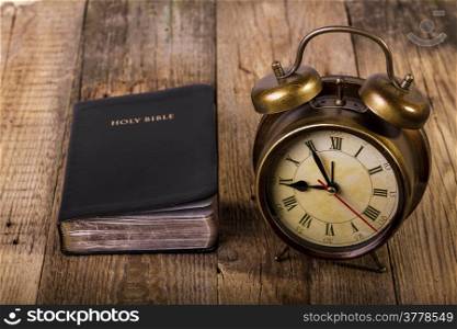 Holly Bible with clock on wood. Focus on clock.