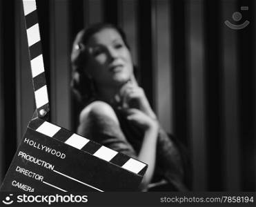 Hollywood black and white, a beautiful acting woman and a clapboard - minimal lighting and strong contrast