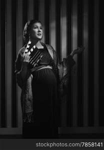 Hollywood black and white, a beautiful pregnant woman and she holds a clapboard - minimal lighting and strong contrast