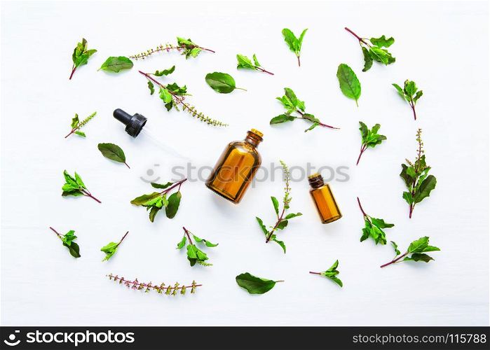 Holy Basil Essential Oil in a Glass Bottle with Fresh Holy Basil white wooden background.